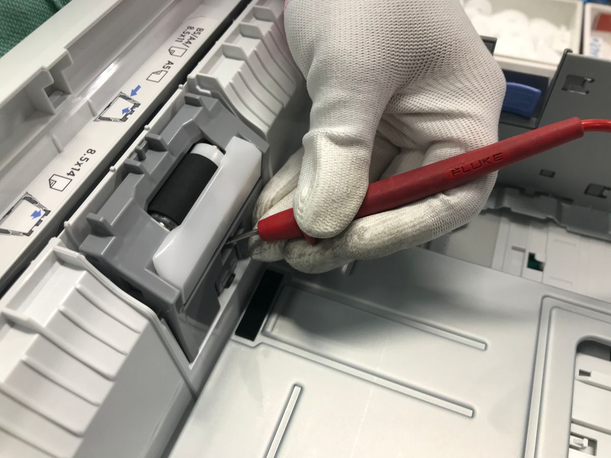Technician repairing an HP printer paper path with a precision tool
